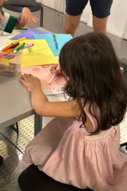 A child drawing on color paper with a marker.